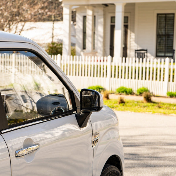 The Wink Mark3, A white low speed electric vehicle (lsv) parked in front of a a white picket fence.