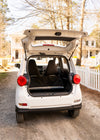 A White Wink Mark3 on a dirt road with it's spacious trunk open, a fully enclosed LSV