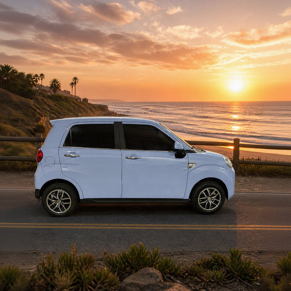 White vehicle parked on a road with a scenic sunset over the ocean in the background